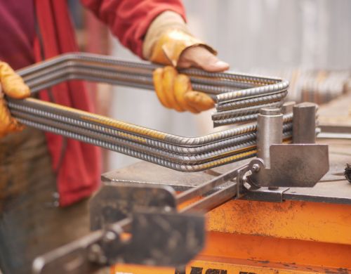 A highly skilled craftsman is expertly using clamps to manipulate metal rods within a workshop